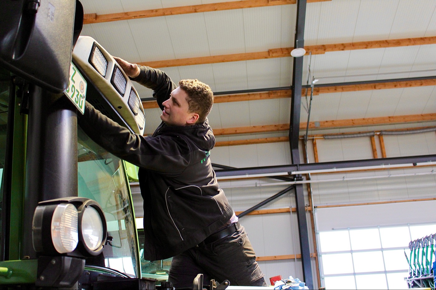 Arbeit an der Frontbeleuchtung eines Traktors in der Halle